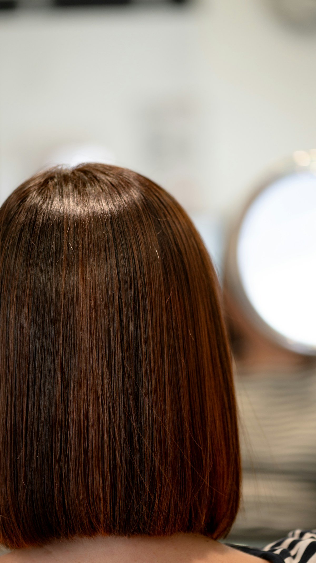 Sleek brown bob haircut viewed from behind, showing a clean perimeter and polished shape