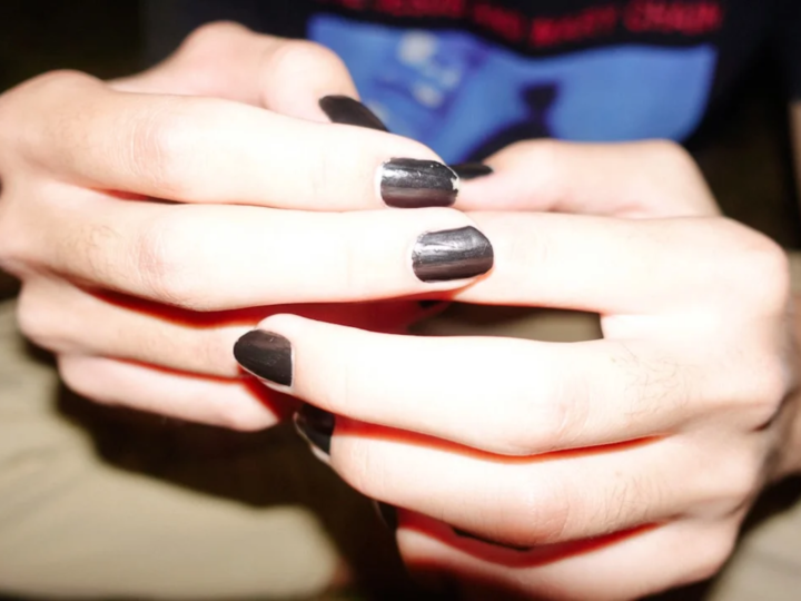 Hands with deep dark nails in a soft matte manicure finish
