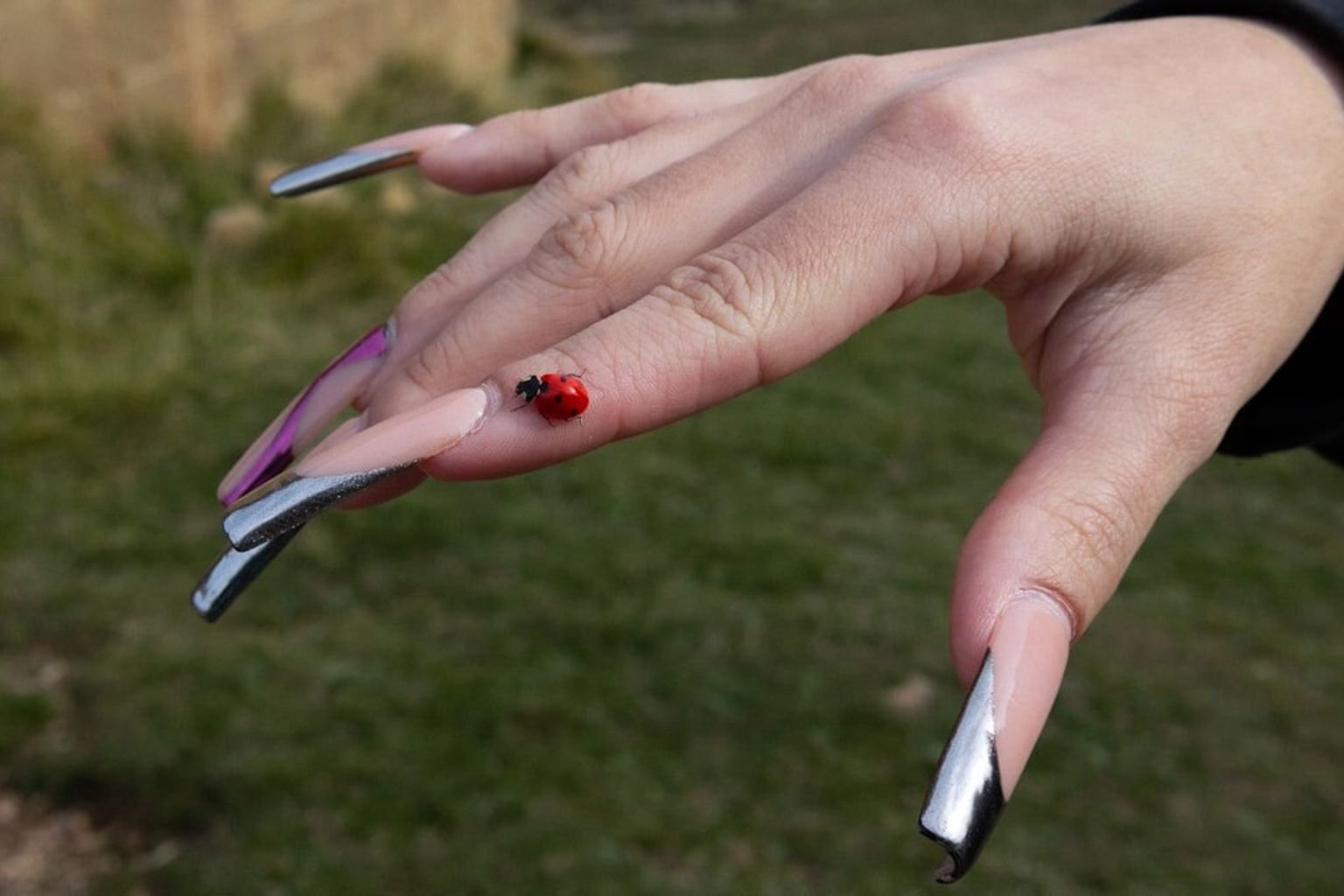 Close-up manicure with reflective silver metallic details and a liquid-metal finish