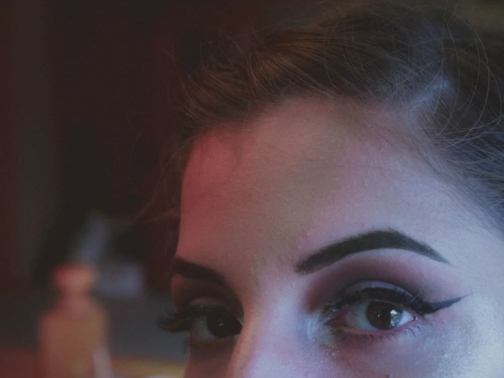 Close-up portrait with soft plum-toned eye makeup blended around the lash line