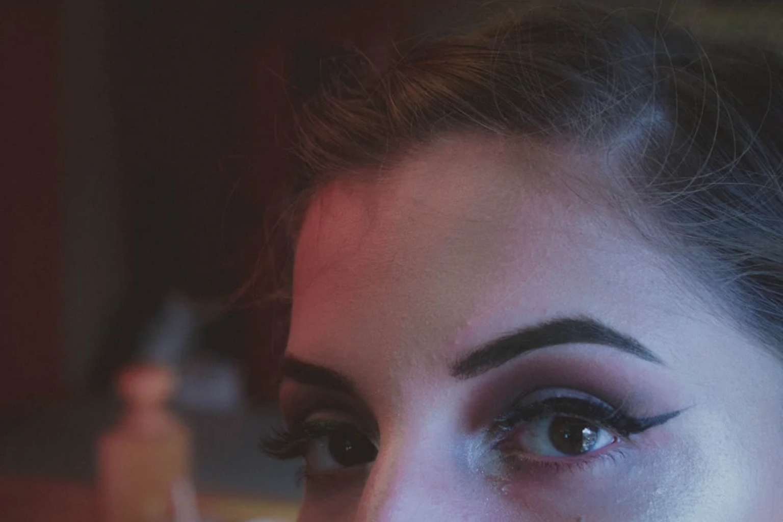 Close-up portrait with soft plum-toned eye makeup blended around the lash line