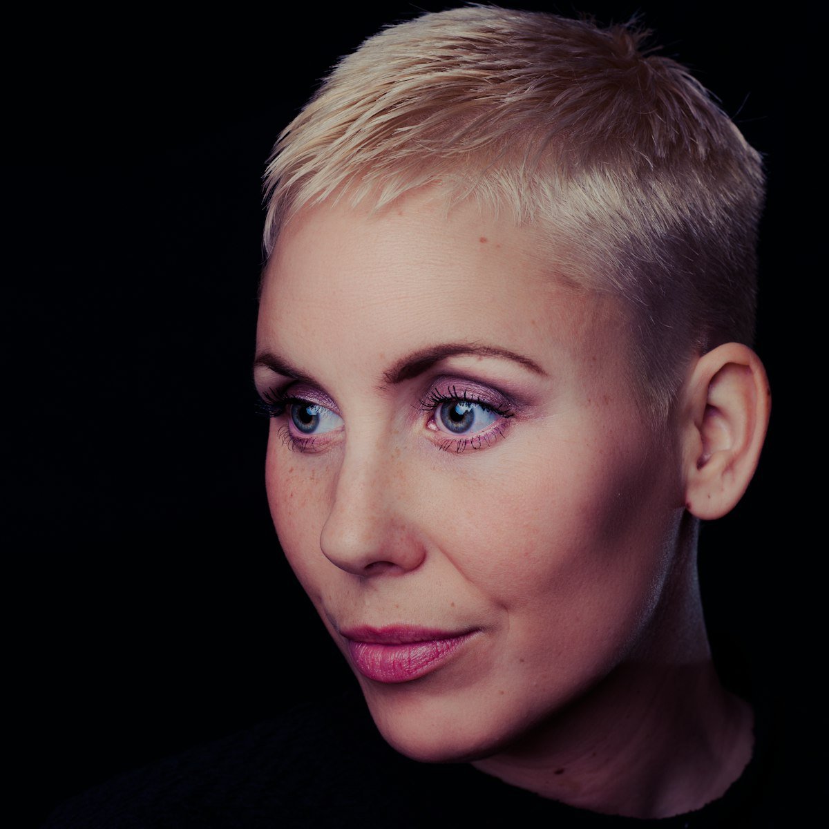 Woman with a short blonde pixie-style haircut showing soft fringe and textured movement