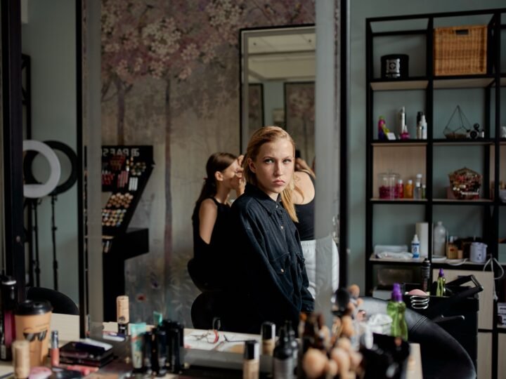 Woman considering her look in a beauty salon mirror surrounded by styling products