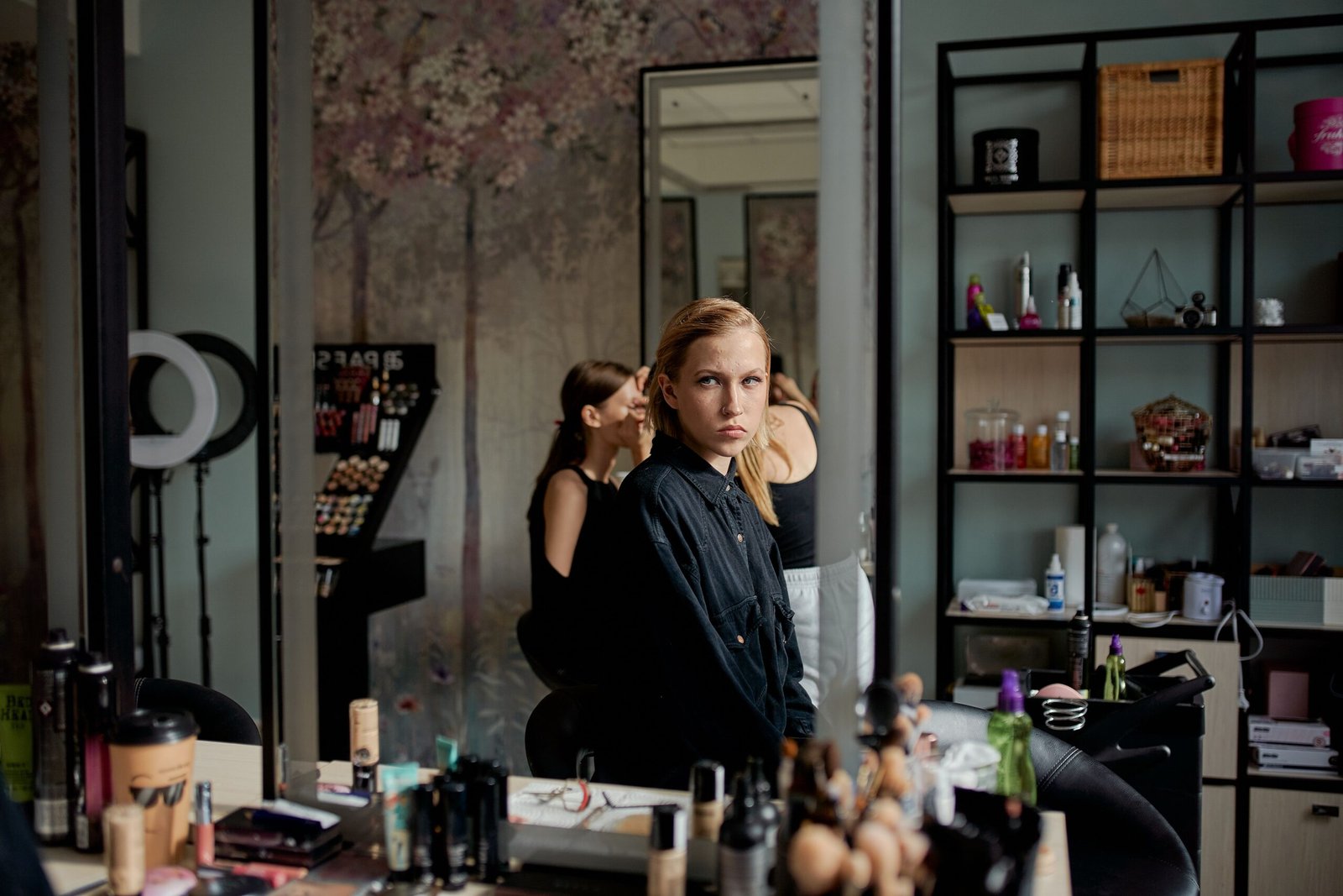 Woman considering her look in a beauty salon mirror surrounded by styling products